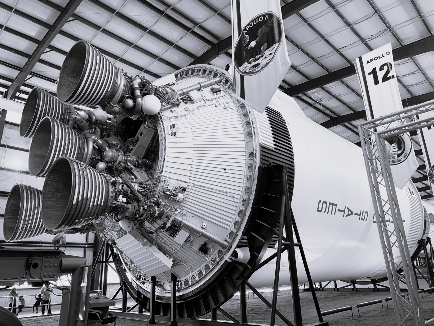 Rocket engine nozzles on a Saturn V stage displayed in a hangar.